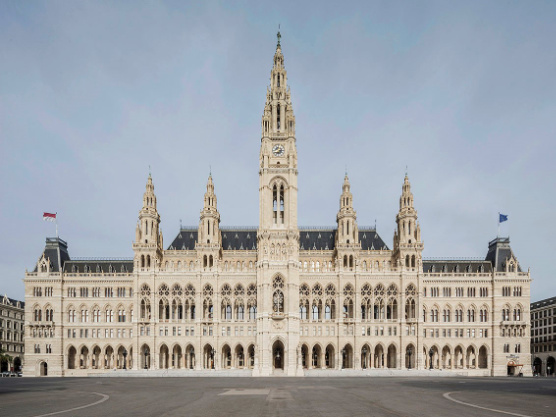 frontale Ansicht des Wiener Rathauses, helles neogotisches Gebäude mit fünf Türmen, wobei der mittlere besonders hoch ist